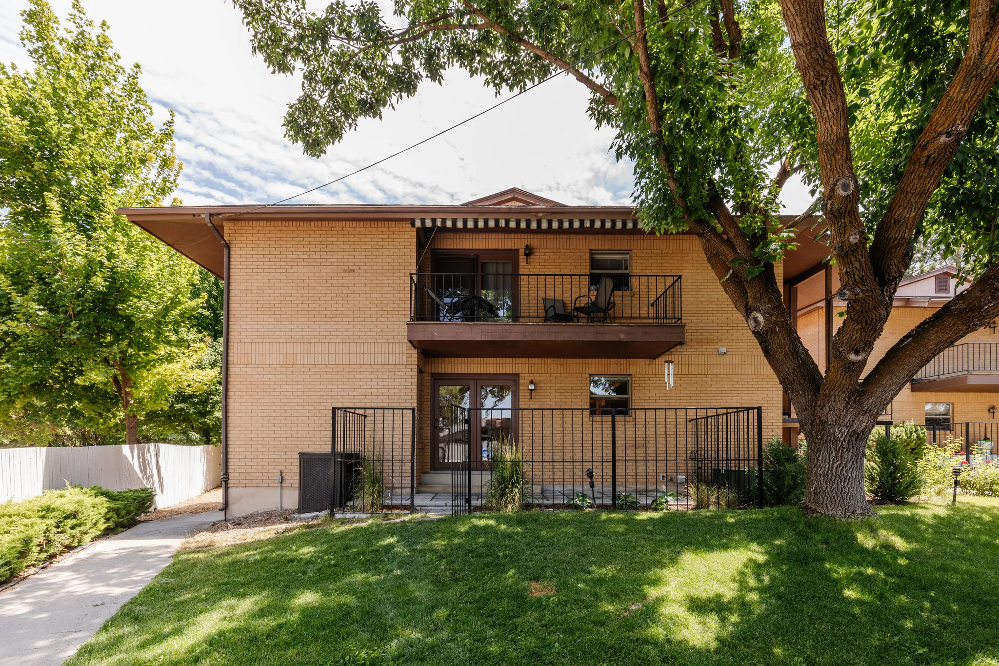 Brick exterior featuring a private upper balcony with iron railings and an awning