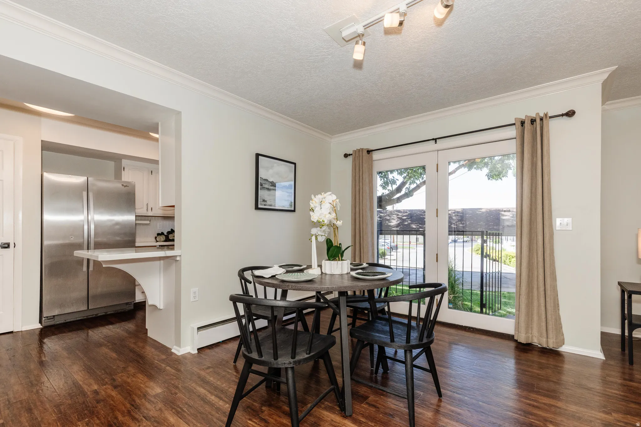 Dining area featuring wood-finish flooring, crown molding, and track lighting