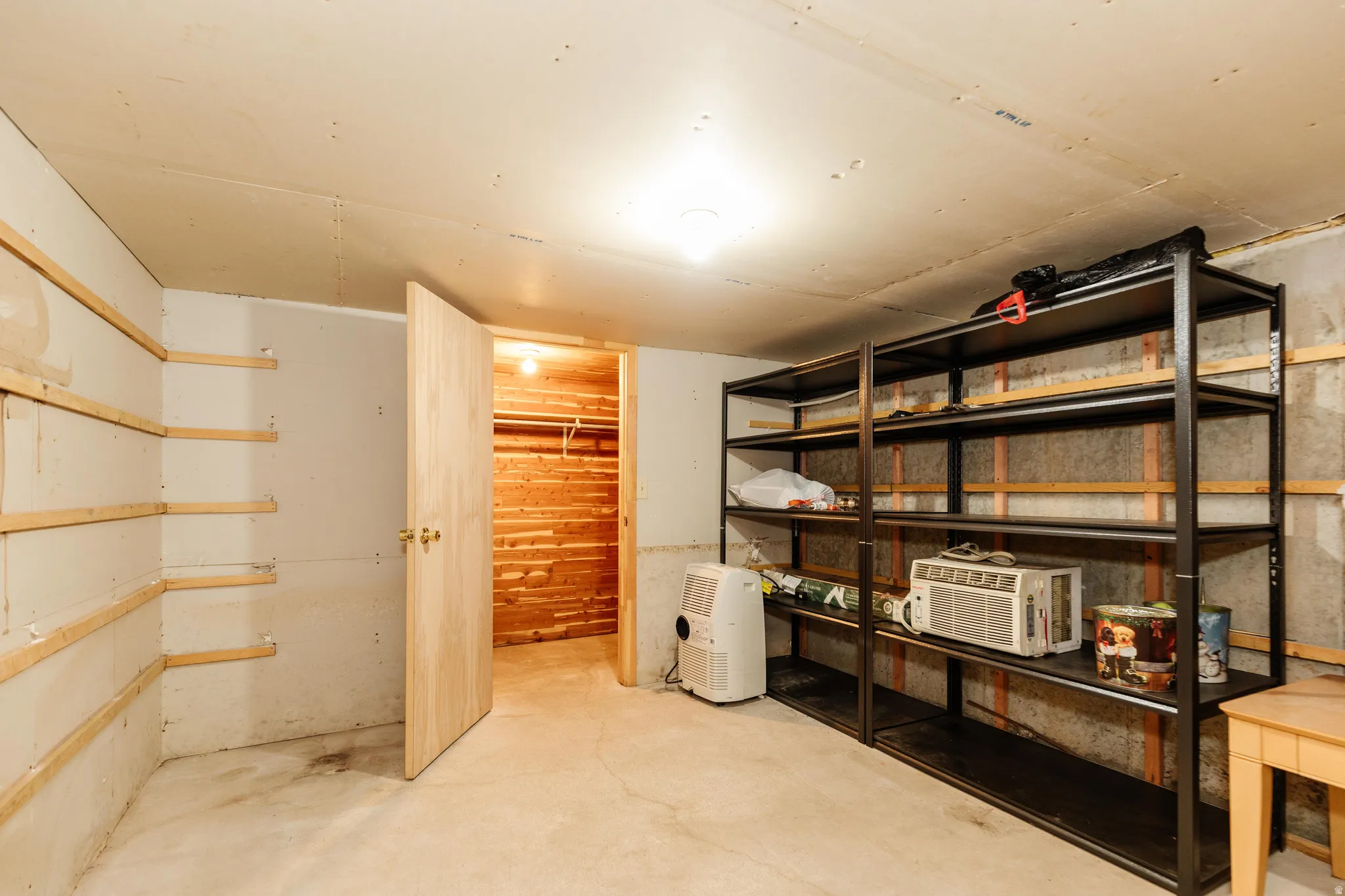 Utility room featuring a concrete floor, built-in shelving, and a wood-paneled closet