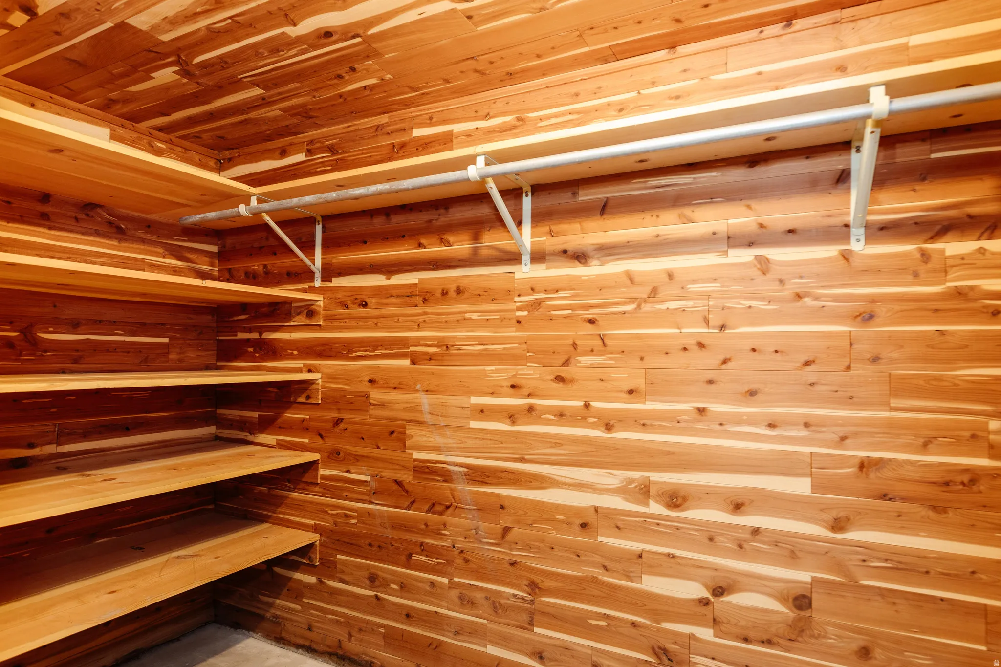 Custom closet featuring cedar plank walls and ceiling, built-in shelving, and a metal hanging rod