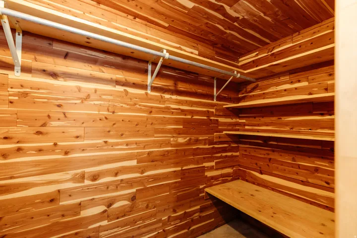 Cedar-lined closet featuring a full-length clothes rod, integrated shelving, and a built-in bench
