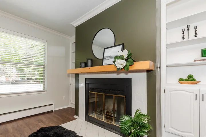Fireplace with a natural wood mantel, white tiled surround, and dark green accent wall