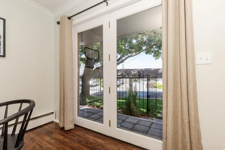 White French doors leading to an exterior patio with stone pavers and a black metal fence