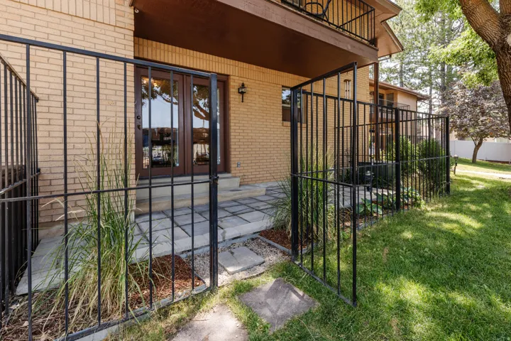 Exterior patio area featuring double French doors, a paver patio, brick facade, and a wrought iron fence