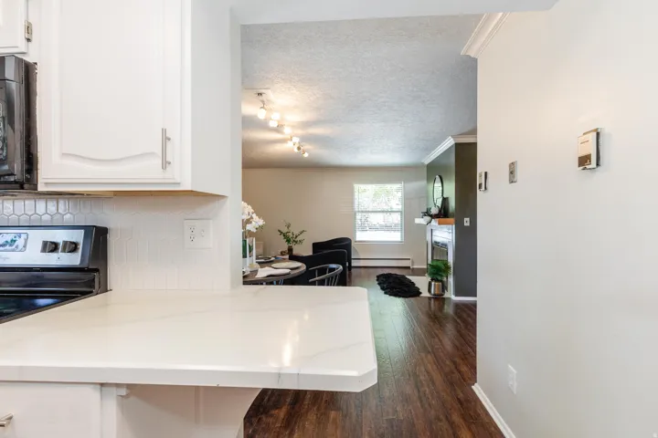Kitchen pass-through featuring light-toned countertops and a white hexagonal tile backsplash