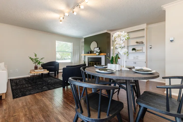 Open-concept living area featuring wood-finish flooring, a fireplace with a wood mantel, and built-in shelving