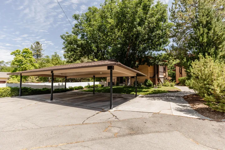 Covered parking structure with multiple bays, asphalt surface, and surrounding mature trees and landscaping