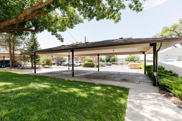 Covered parking structure with multiple bays, asphalt shingle roofing, and dark support pillars