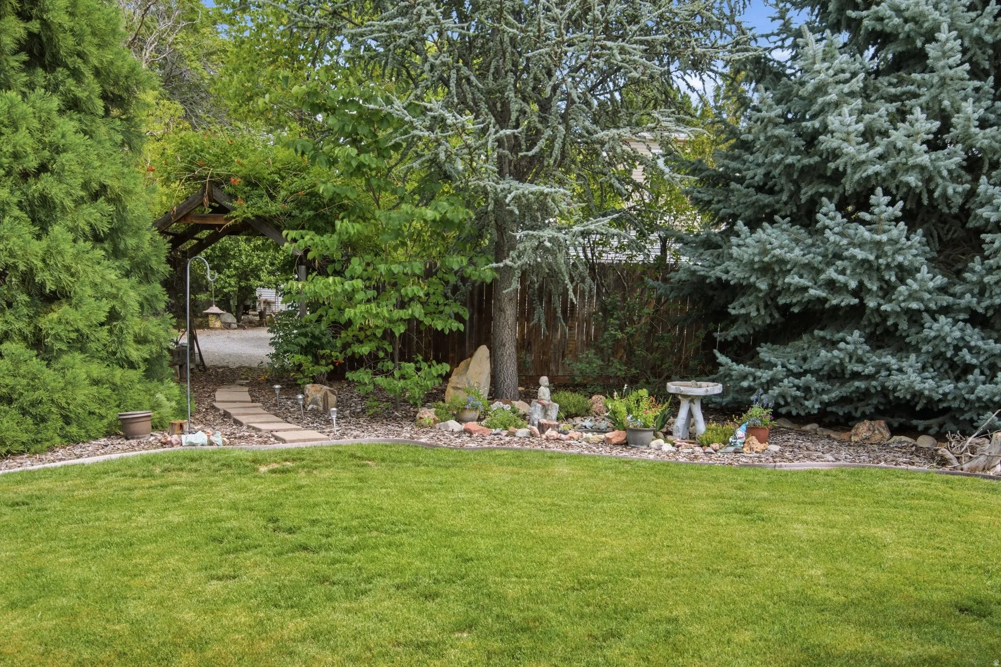 Manicured lawn with mature evergreen trees and a stone pathway