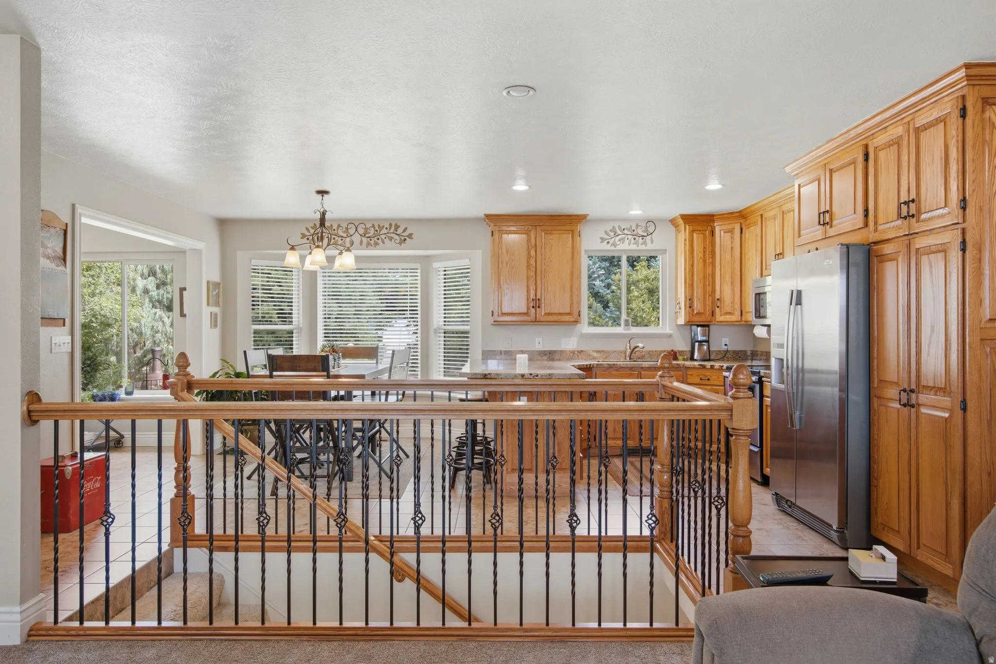 Open concept kitchen and dining area featuring wood cabinetry, stainless steel appliances, bay windows, and recessed lighting