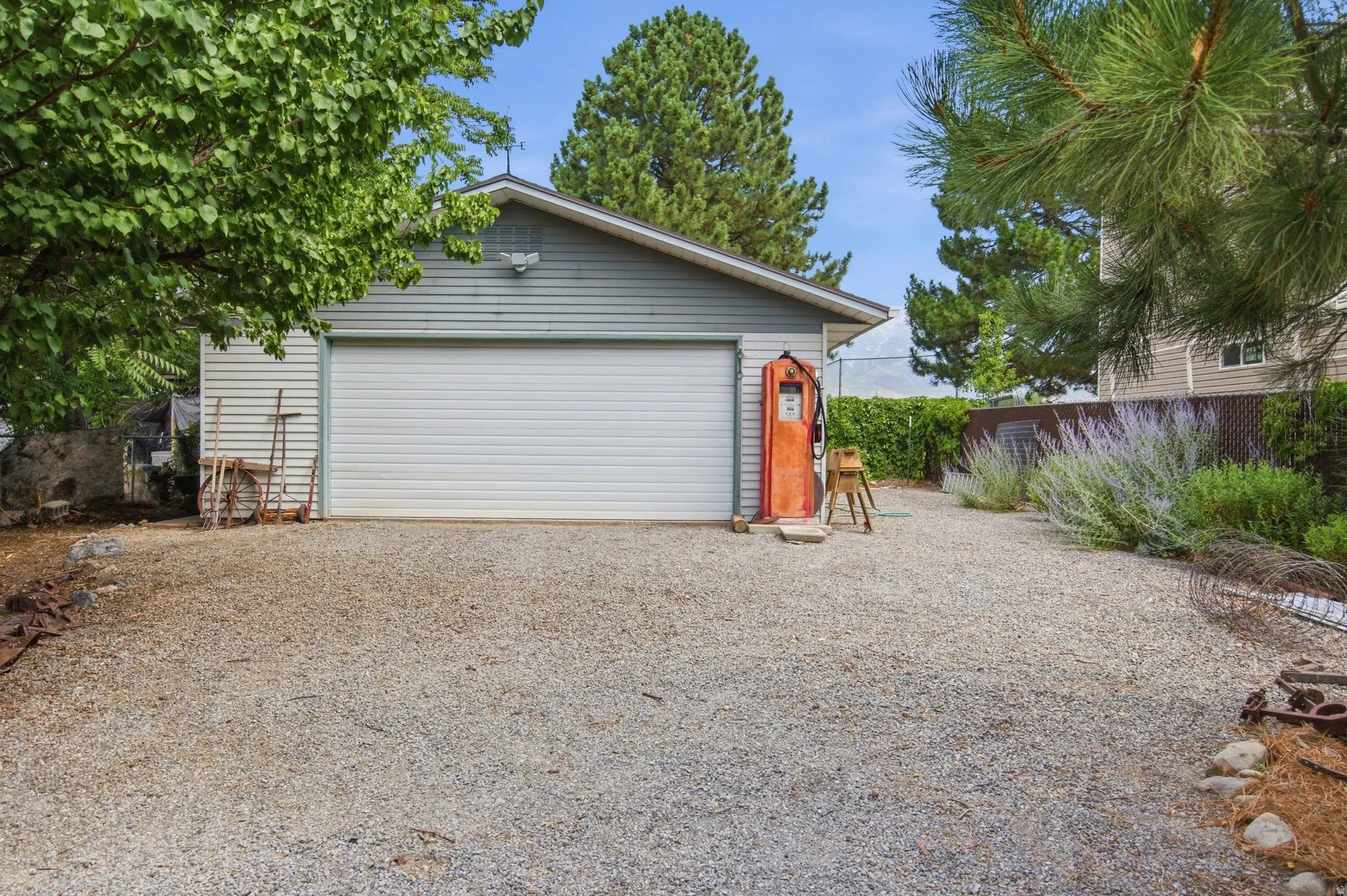 Detached garage with horizontal siding, a single overhead door, and a gravel driveway