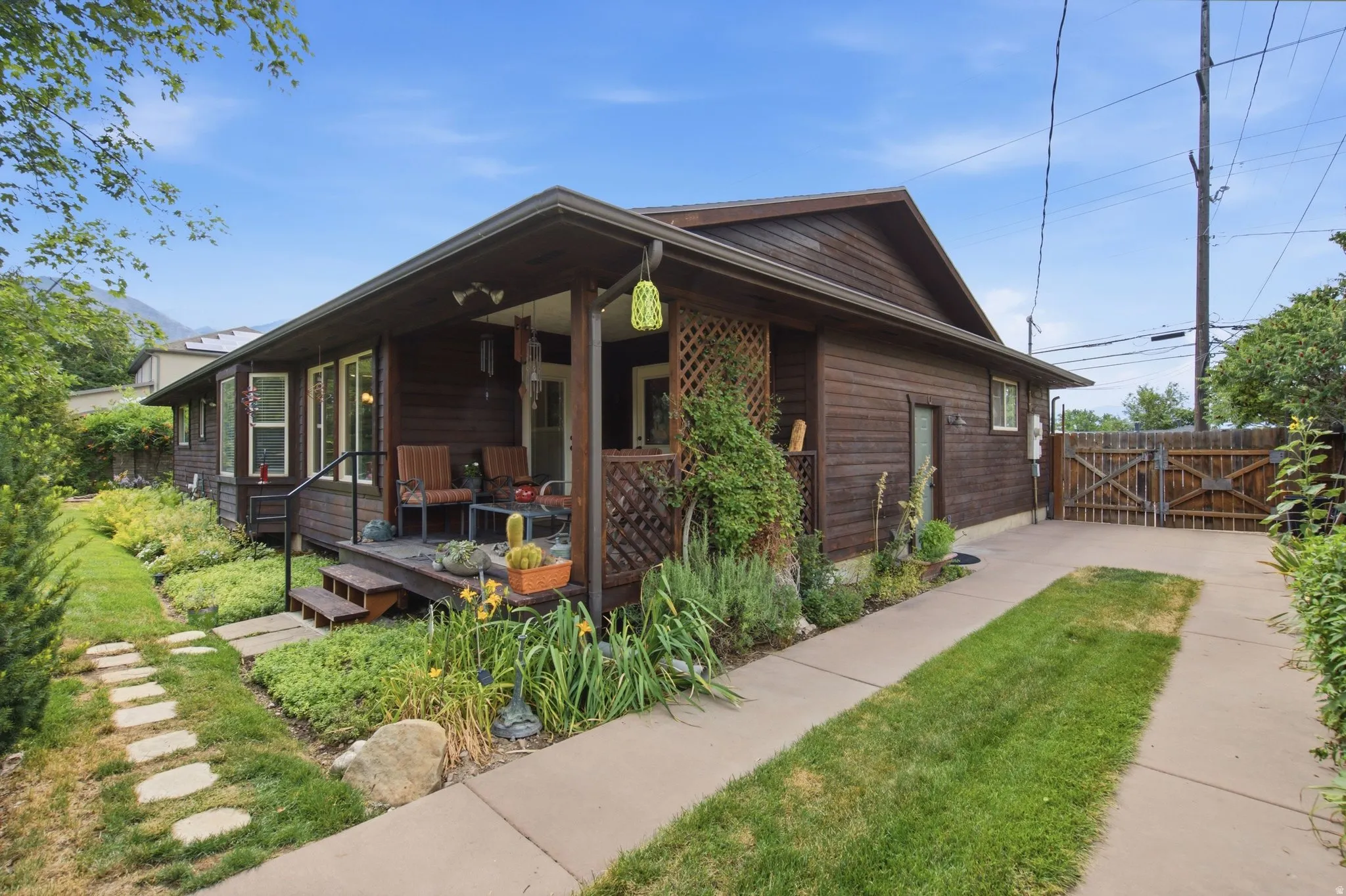 Wood-sided residence featuring a covered front porch, concrete driveway, and a gated wooden fence