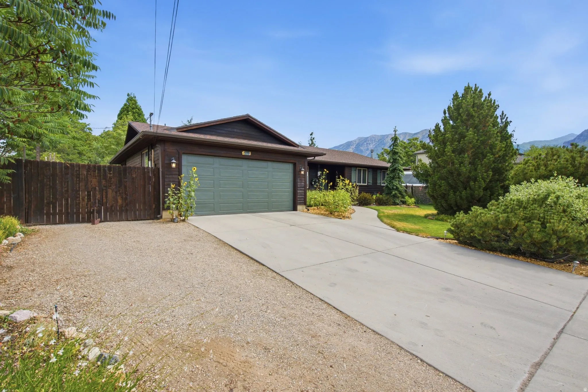 Ranch-style exterior with dark wood siding and a matching wooden fence