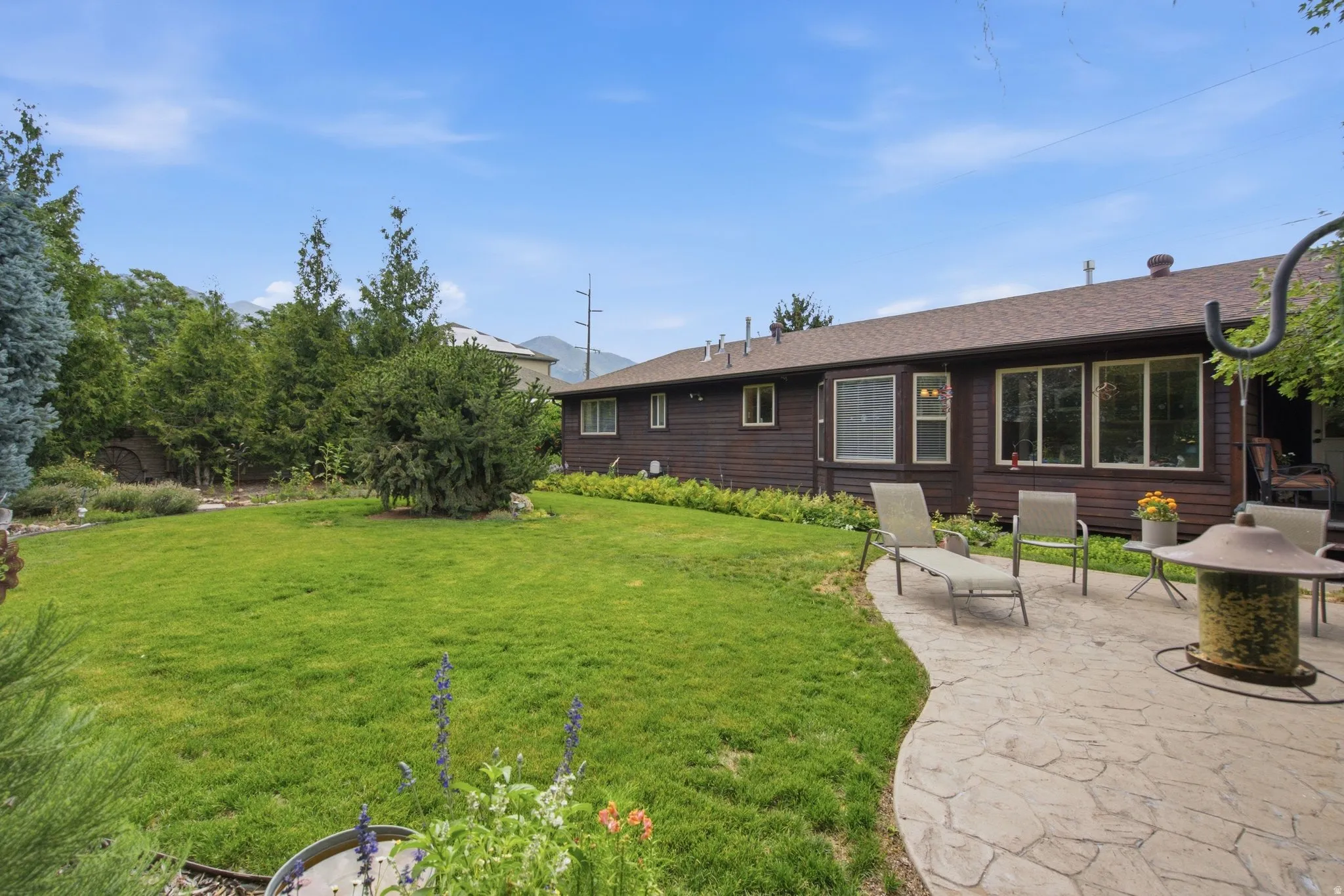 Expansive backyard featuring a manicured lawn, stamped concrete patio, and mature trees