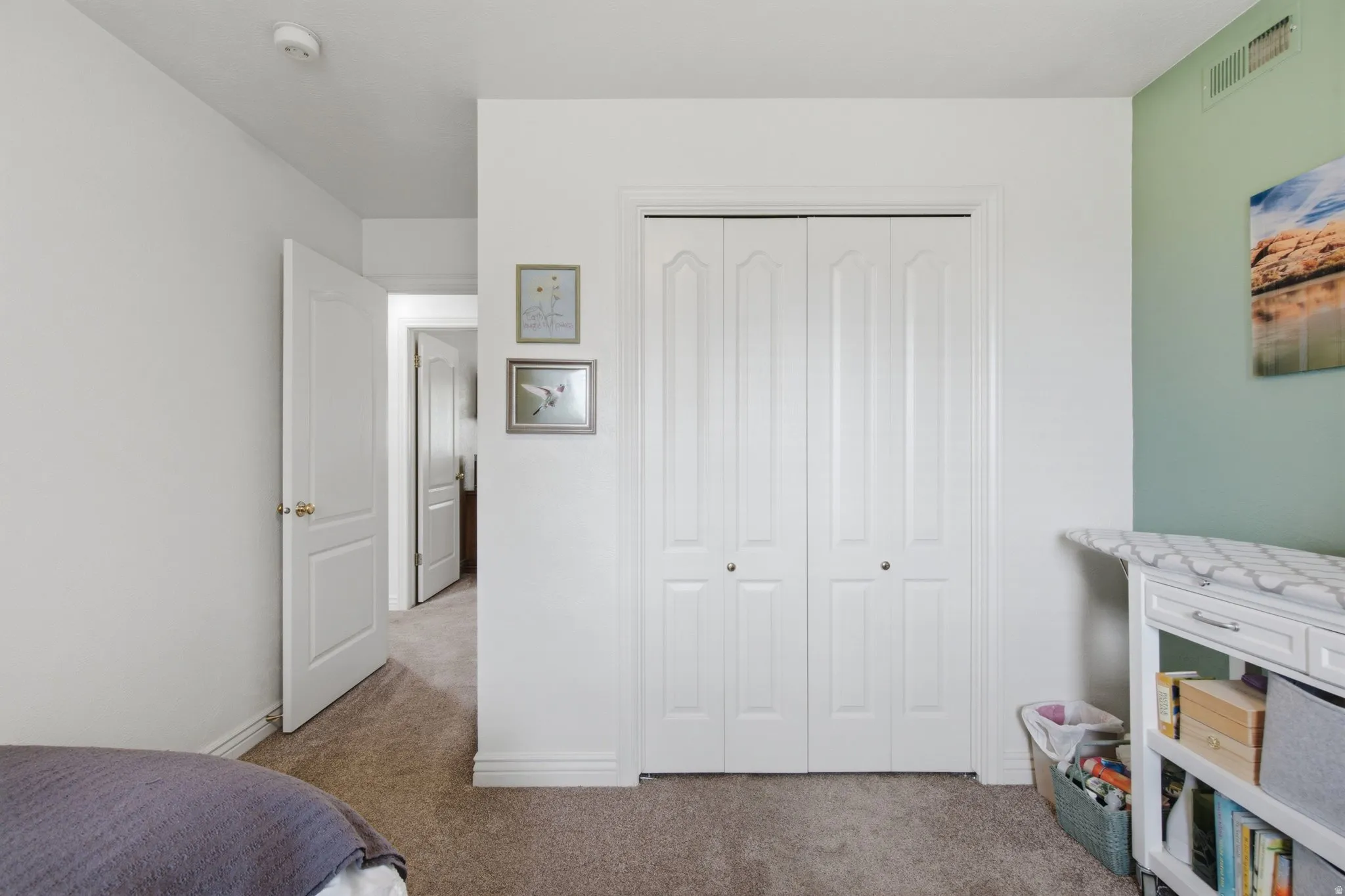 Carpeted room featuring a double bifold closet door and a light-colored wall with a contrasting accent wall