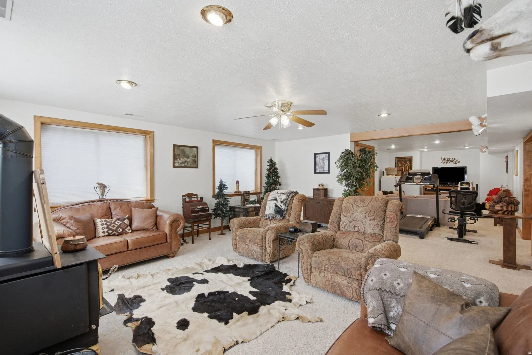 Spacious living area featuring a black wood-burning stove with a metal flue, natural wood window trim, and recessed lighting
