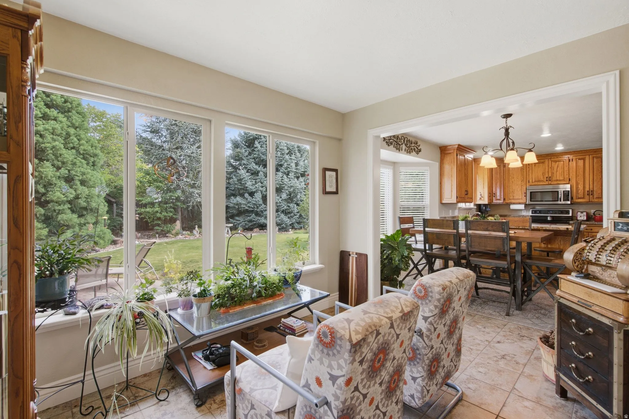 Bright sunroom with multiple large windows, tile flooring, and direct sight to the kitchen