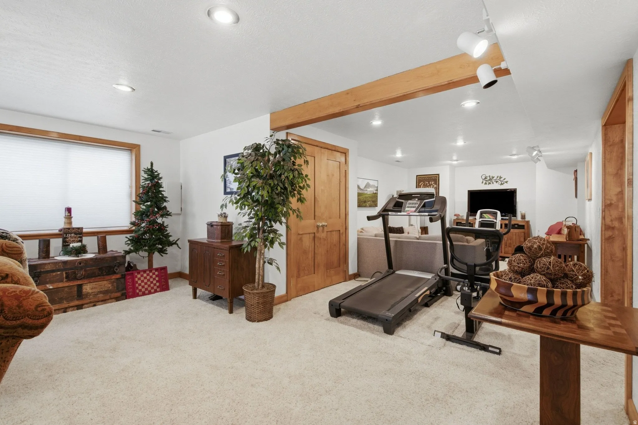 Finished lower level featuring recessed lighting, a wooden support beam, light-colored carpeting, a window with blinds, and wood panel doors