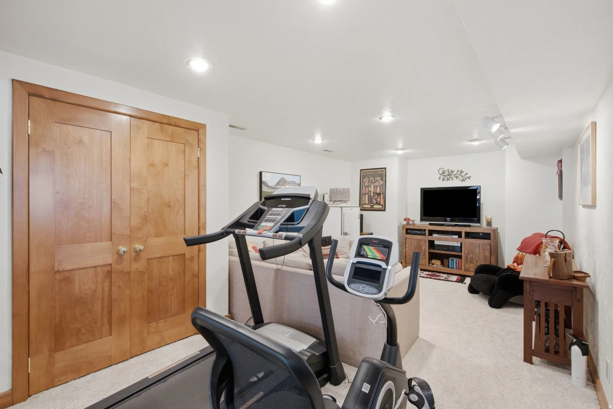 Recessed lighting illuminating a carpeted room with light wood double bi-fold doors