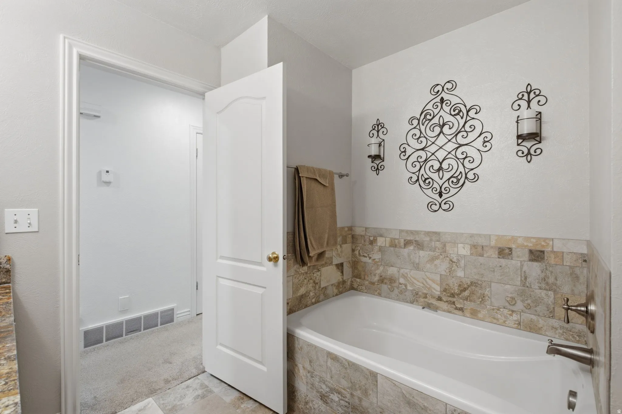 Soaking bathtub with stone tile surround and brushed nickel fixtures