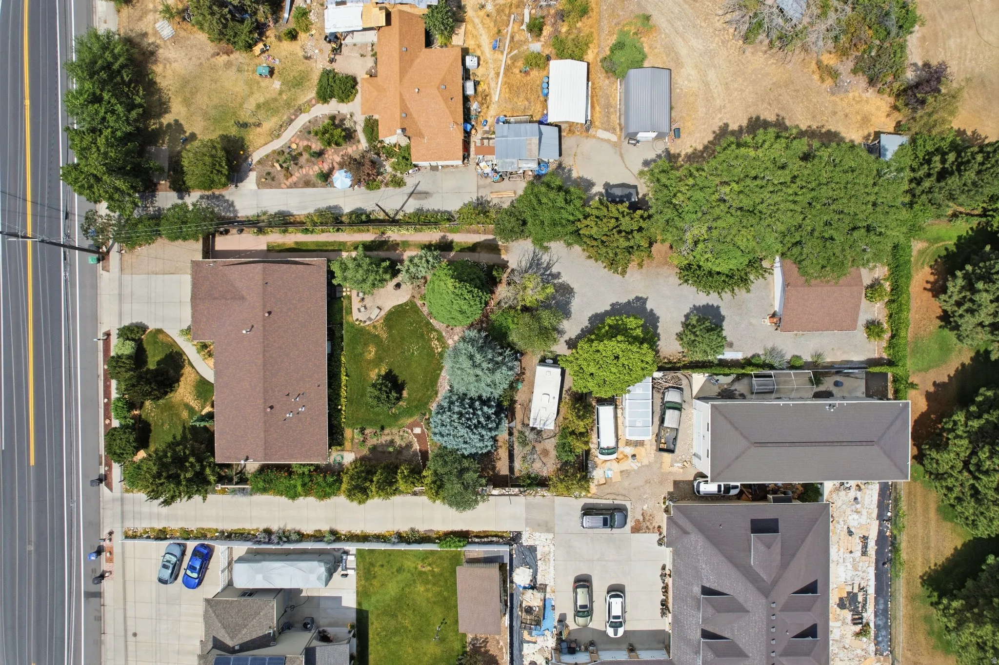 The property features a brown shingle roof, a paved driveway, and established landscaping with mature trees and green lawns