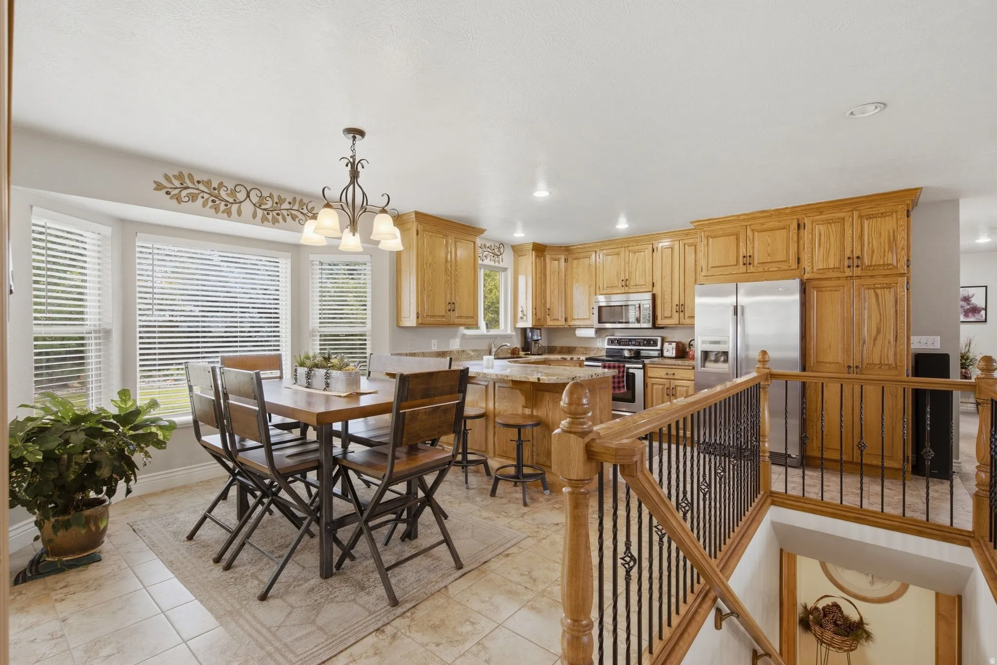 Open-concept kitchen and dining area featuring light wood cabinetry, stainless steel appliances, a center island with bar seating, and a bay window