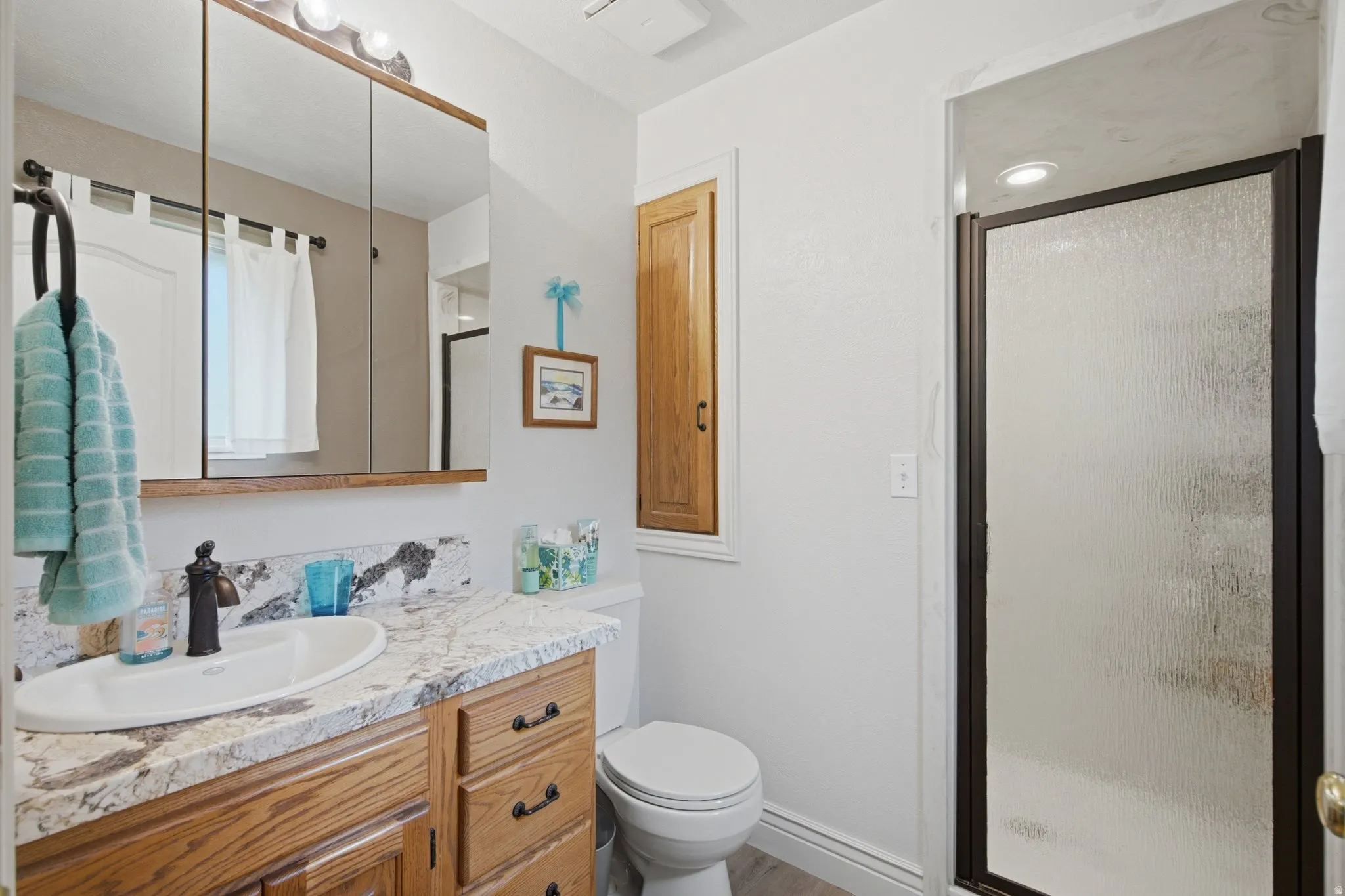Bathroom featuring a wood-finish vanity with a light-colored countertop and integrated sink