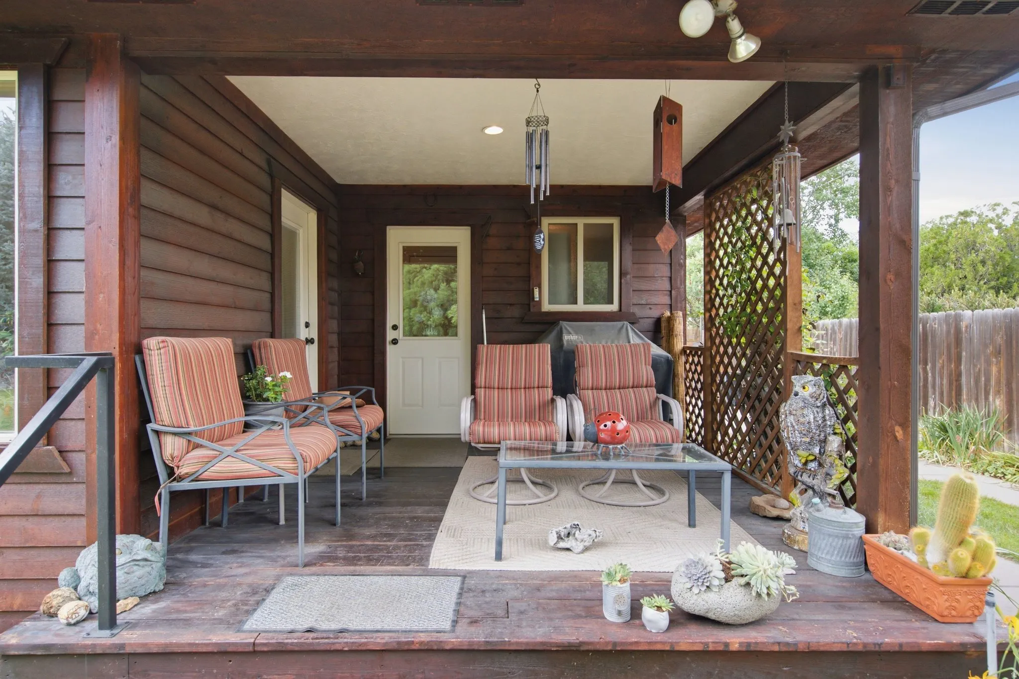 Covered wood-finish deck with horizontal siding, lattice privacy screen, and recessed lighting