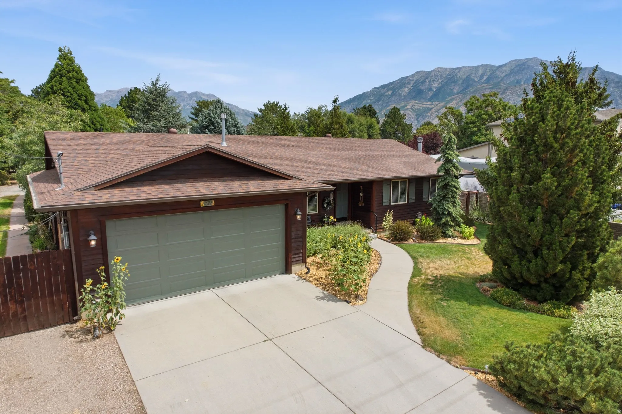 Ranch-style exterior with a two-car garage, concrete driveway, and a winding walkway