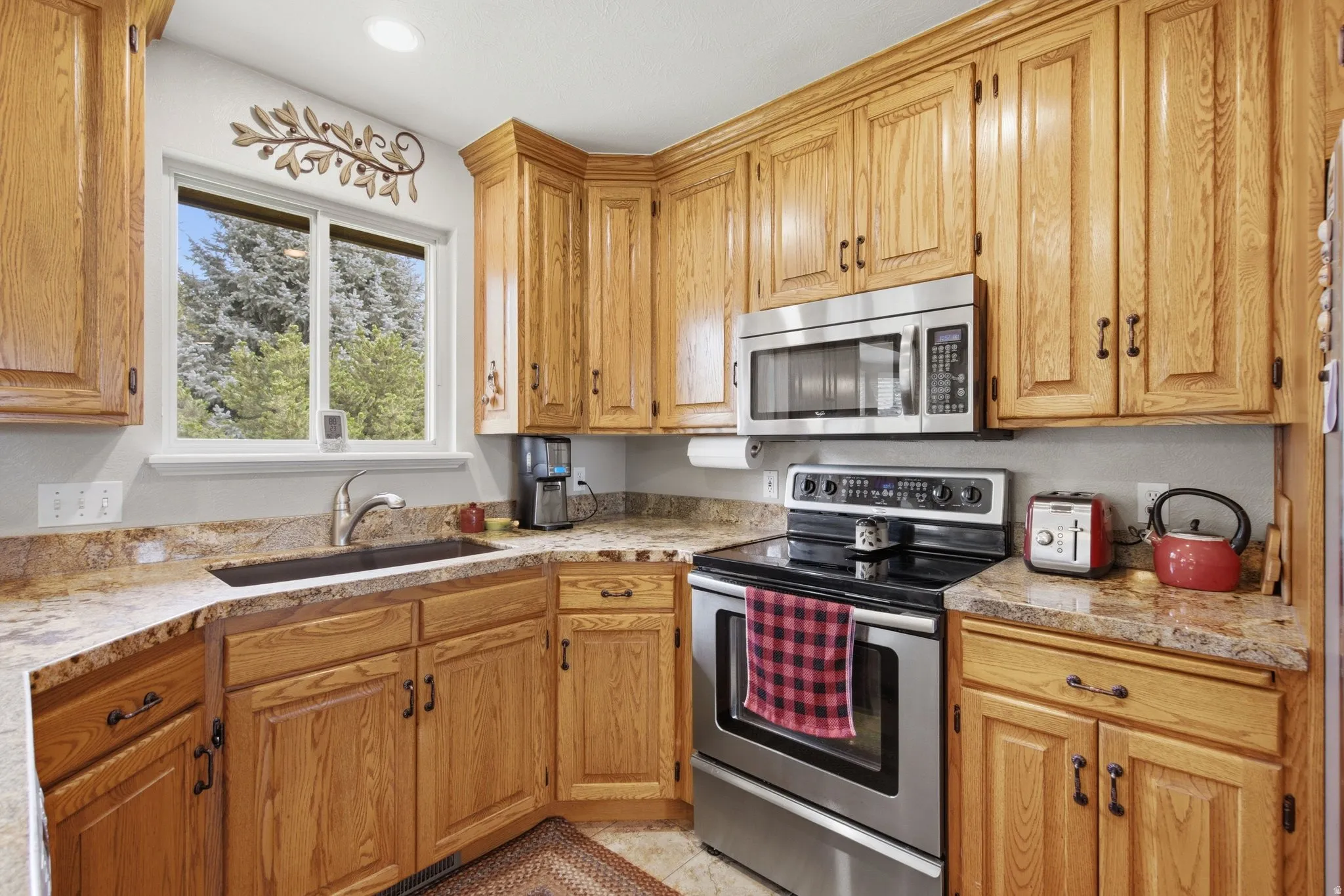 Kitchen featuring wood cabinetry, stainless steel appliances, granite-style countertops, and a double-pane window