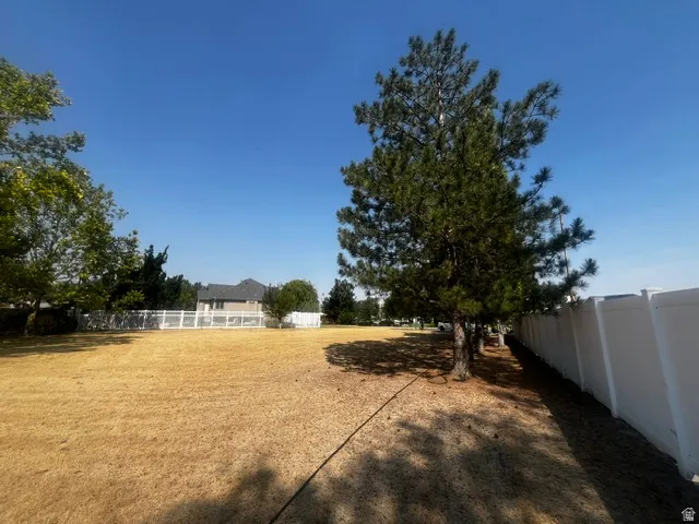 Expansive yard featuring mature trees and a white privacy fence