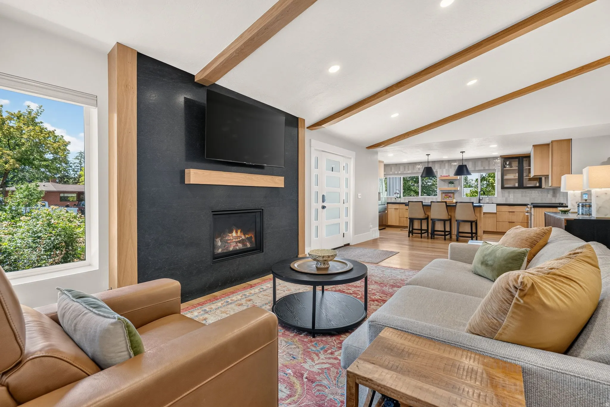 Living area featuring exposed wood beams, a fireplace with a black stone surround, and a wood mantel
