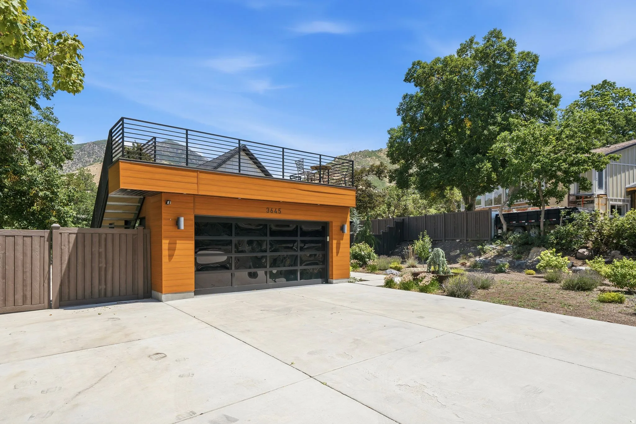 Modern garage structure featuring wood-look metal siding and a sleek glass panel garage door