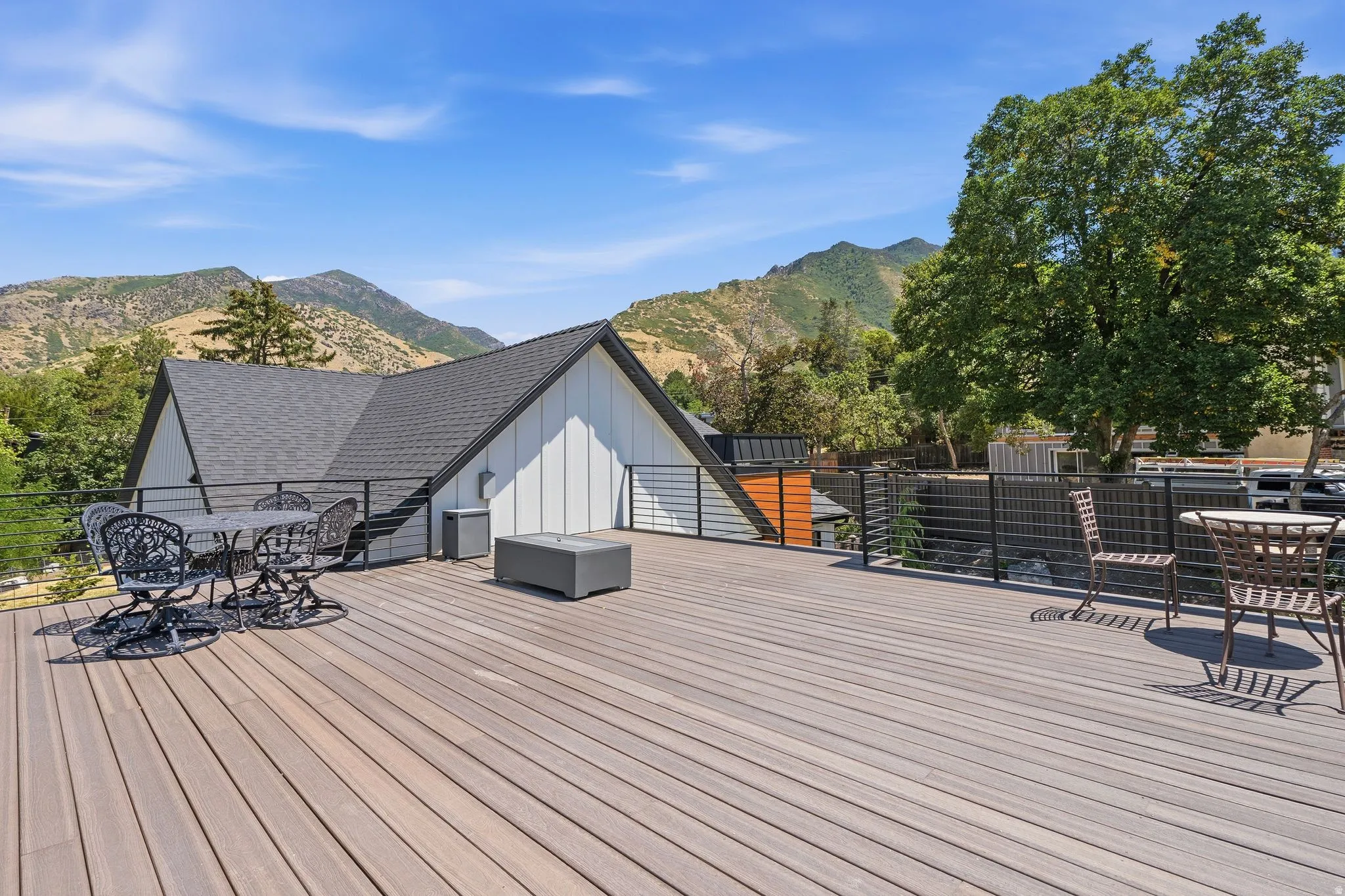 Spacious outdoor deck featuring composite decking, black metal railing, and a modern architectural style with a gabled roofline