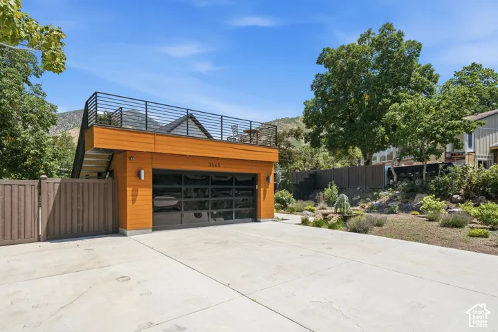 Modern garage structure featuring wood-look metal siding and a sleek glass panel garage door