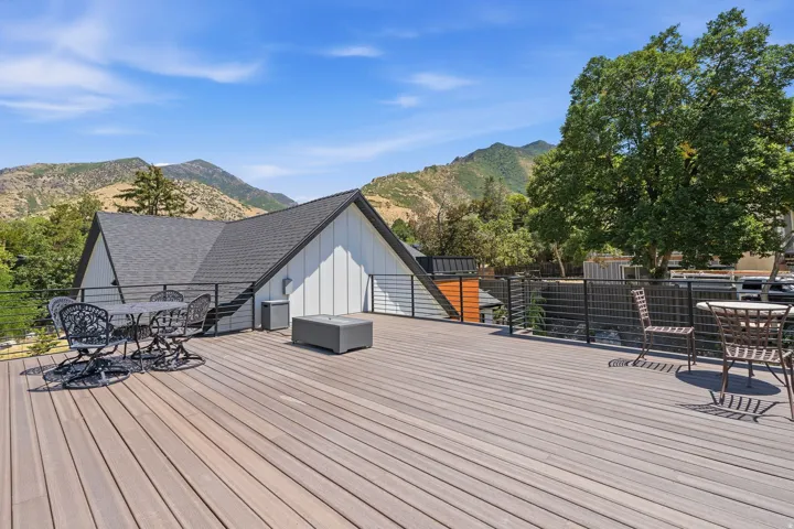 Spacious outdoor deck featuring composite decking, black metal railing, and a modern architectural style with a gabled roofline