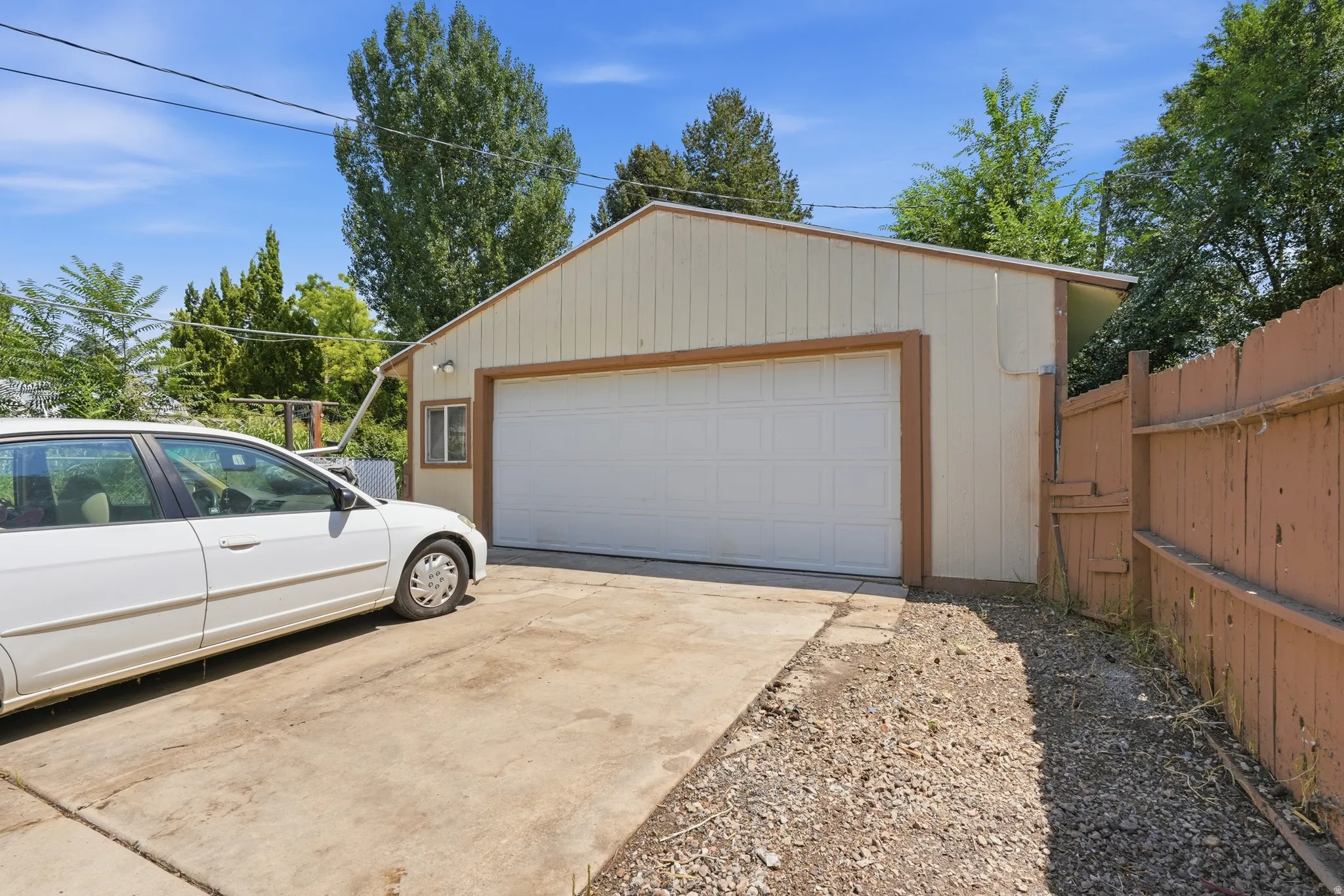 Detached garage with a large overhead door, an exterior wall-mounted light fixture, and a side window
