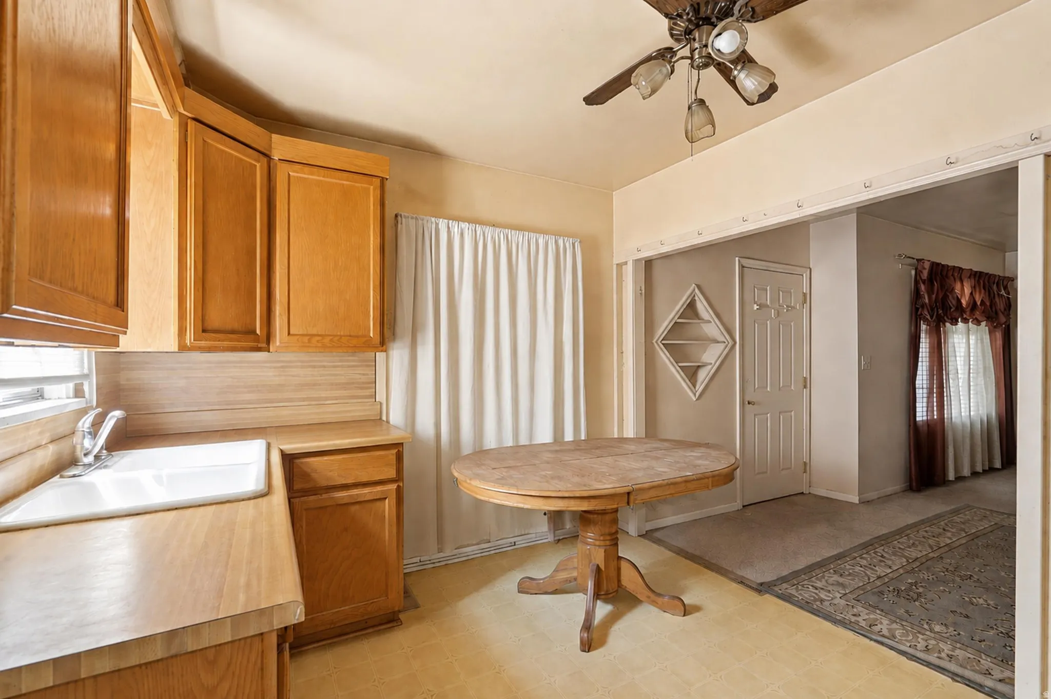 Kitchen area featuring wood-finish cabinetry, a white drop-in sink, and wood-finish countertops
