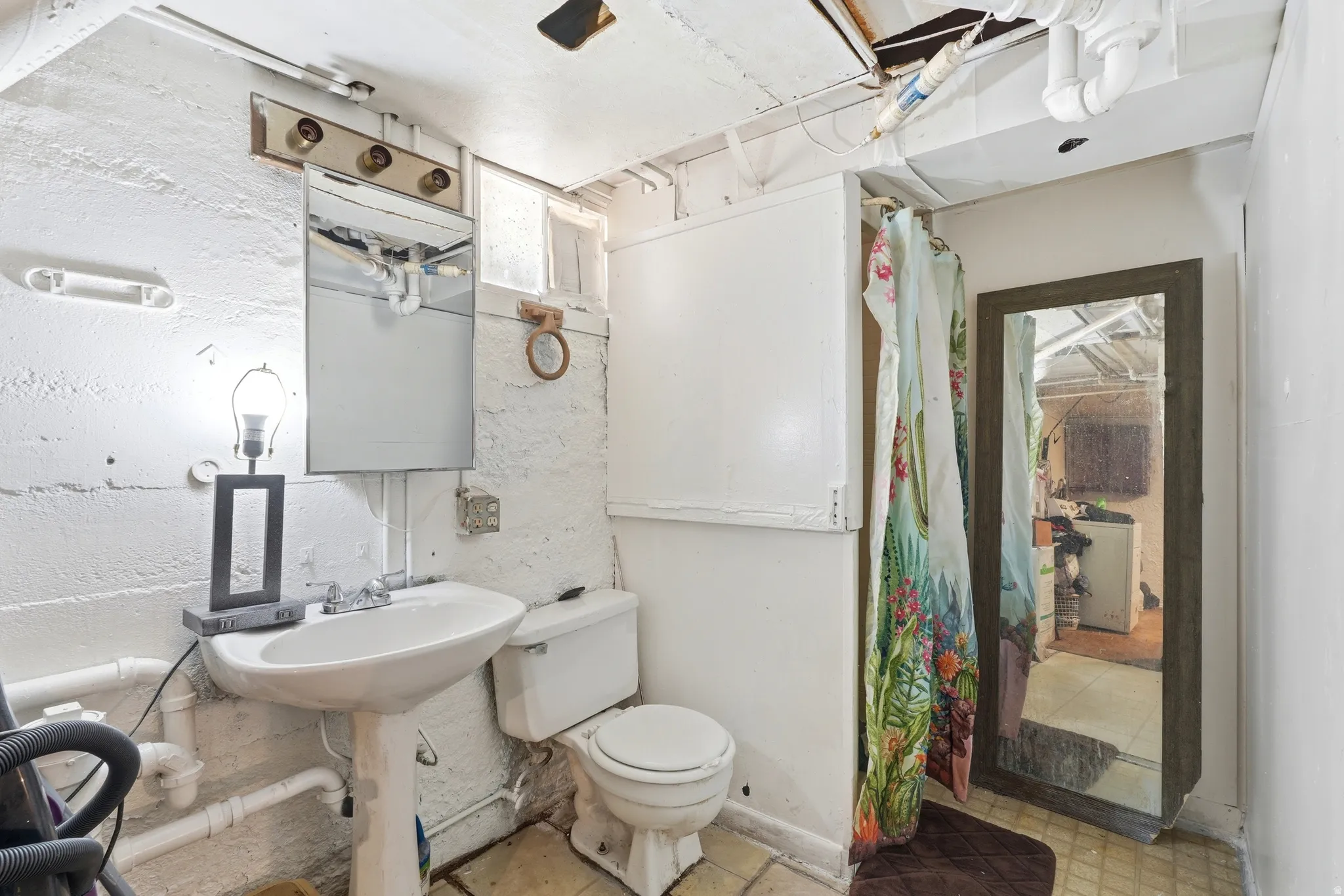 Pedestal sink with chrome fixtures and a vanity mirror