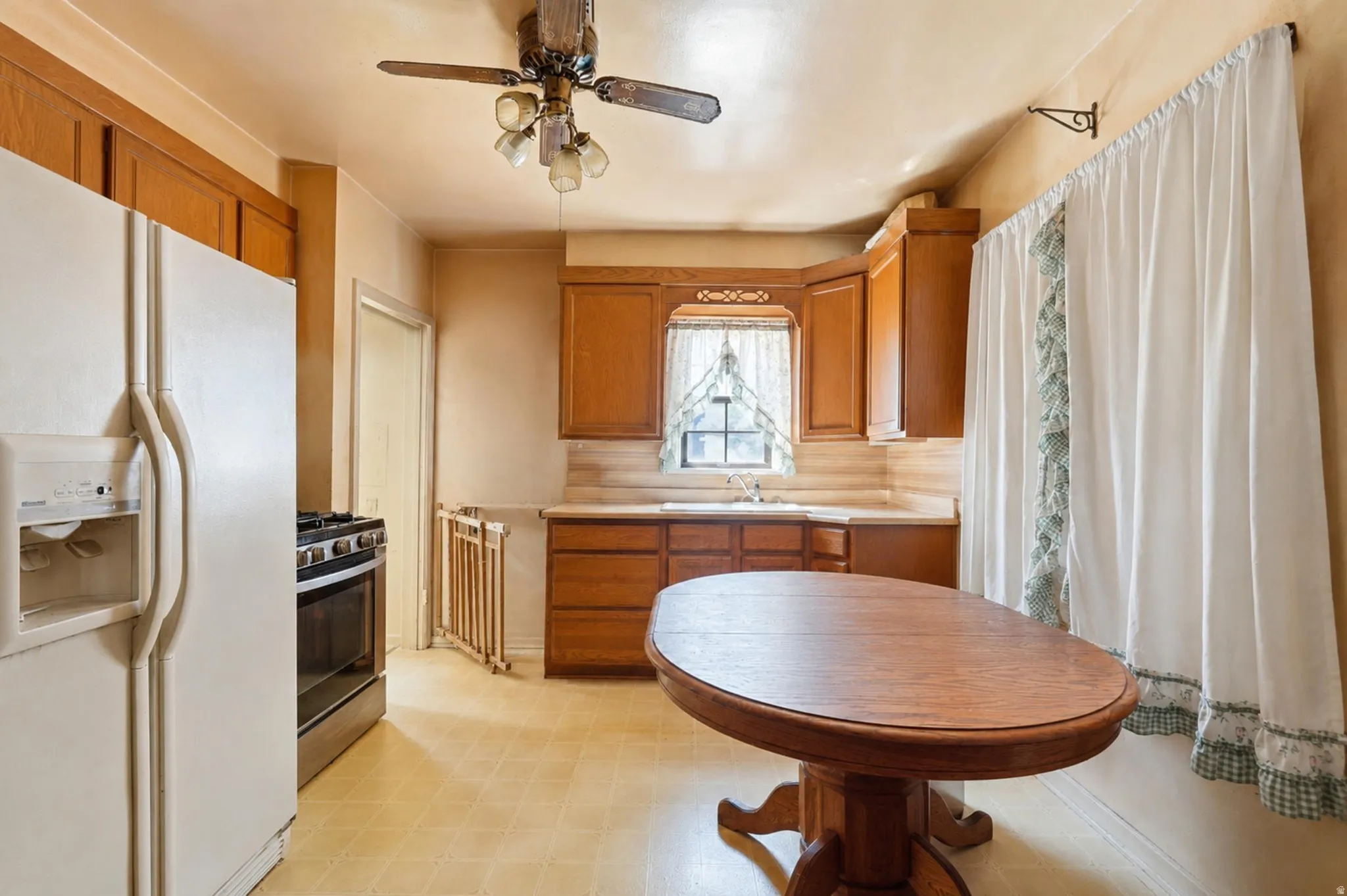 Kitchen featuring wood-finish cabinetry, a stainless steel range, and a ceiling fan