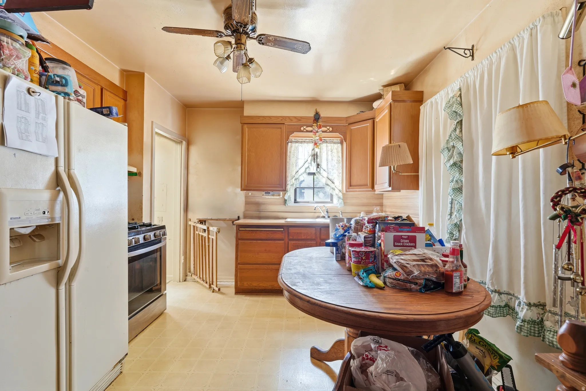 Kitchen featuring wood cabinetry, a window over the sink, and a ceiling fan with integrated lighting