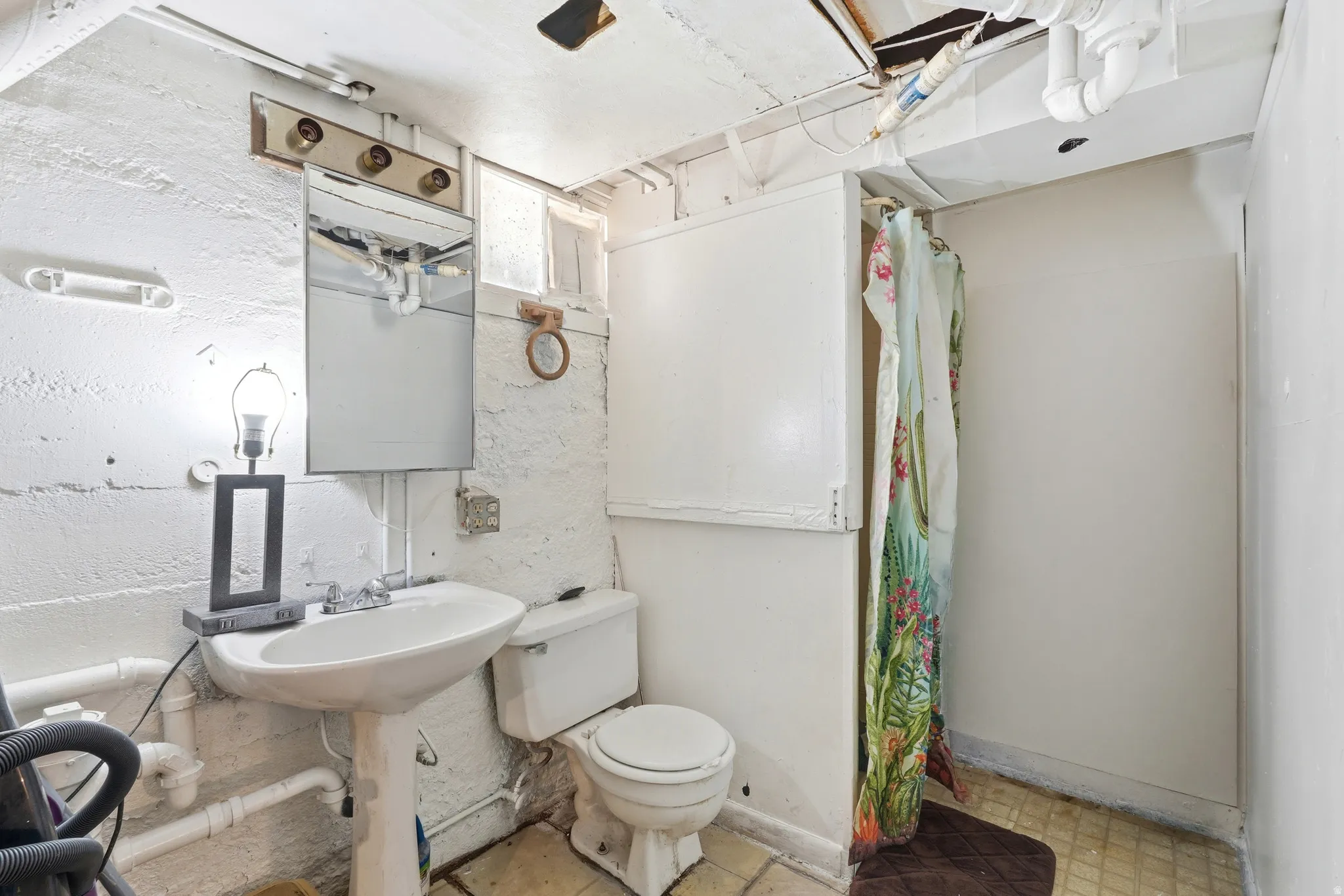 Bathroom featuring a pedestal sink, toilet, and shower area
