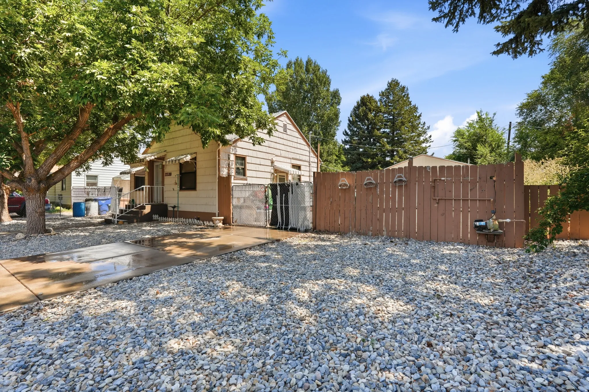 Property exterior featuring a gravel yard and mature trees