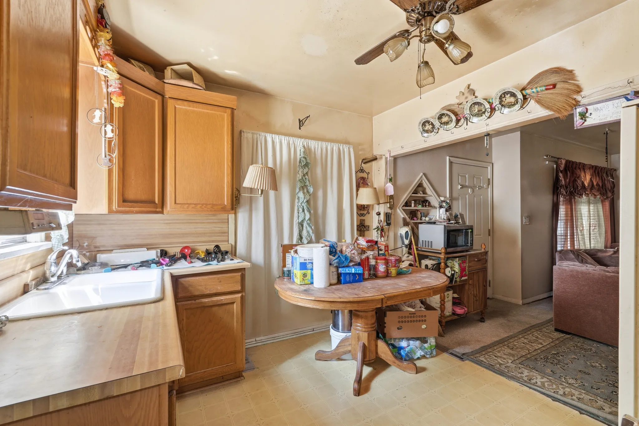 Kitchen area featuring wood-finish cabinetry, a white basin sink, and a ceiling fan with integrated lighting