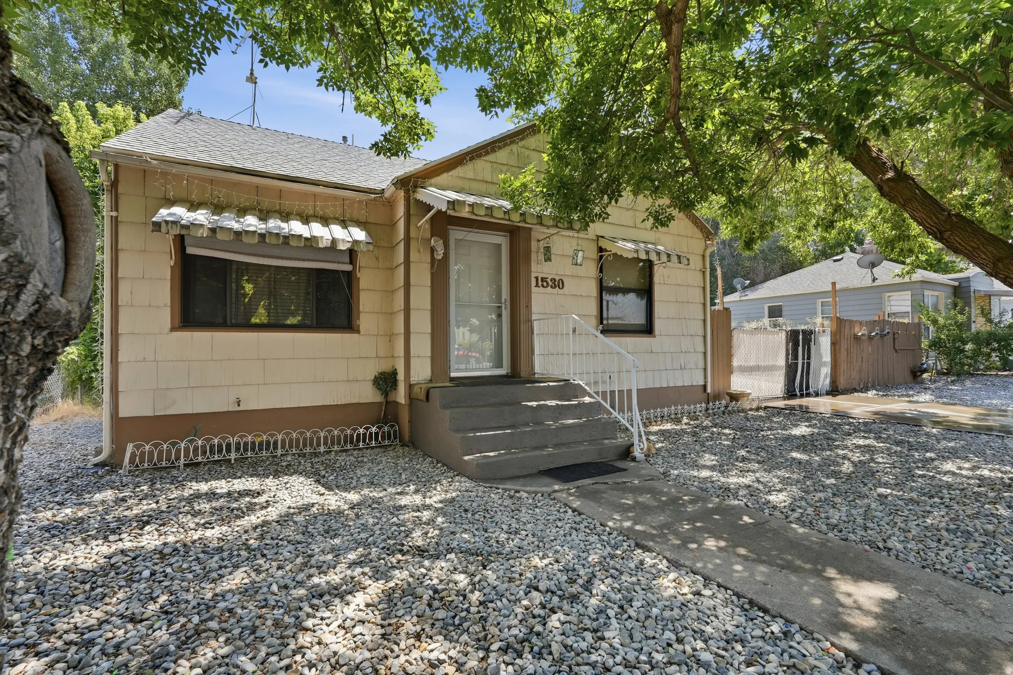 Single-story residence featuring siding exterior, an entrance with an awning, and a stone-covered front yard