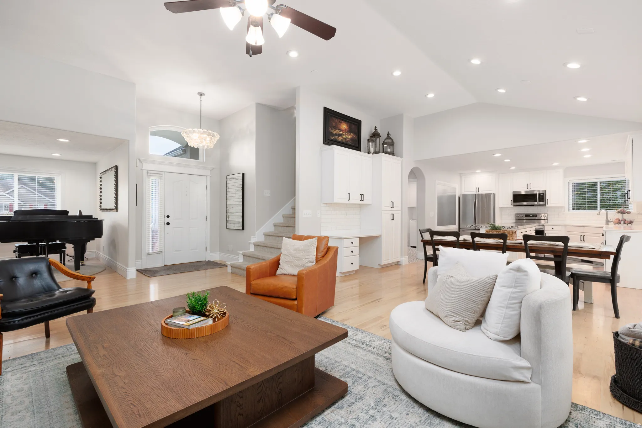 Open concept living space featuring vaulted ceilings, recessed lighting, light wood-finish flooring, and a contemporary ceiling fan