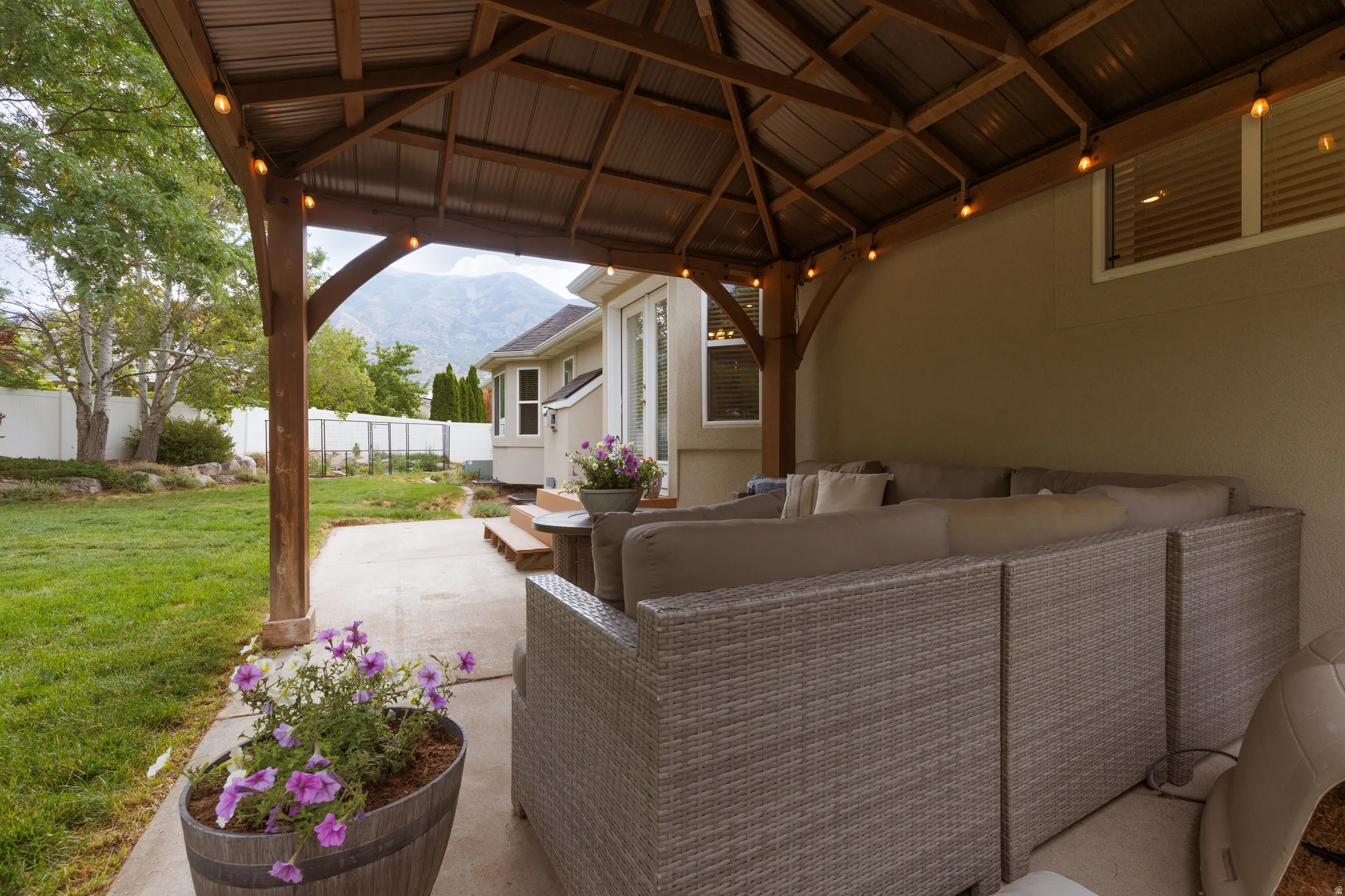 Covered patio featuring a metal roof, exposed wooden beams, and string lighting