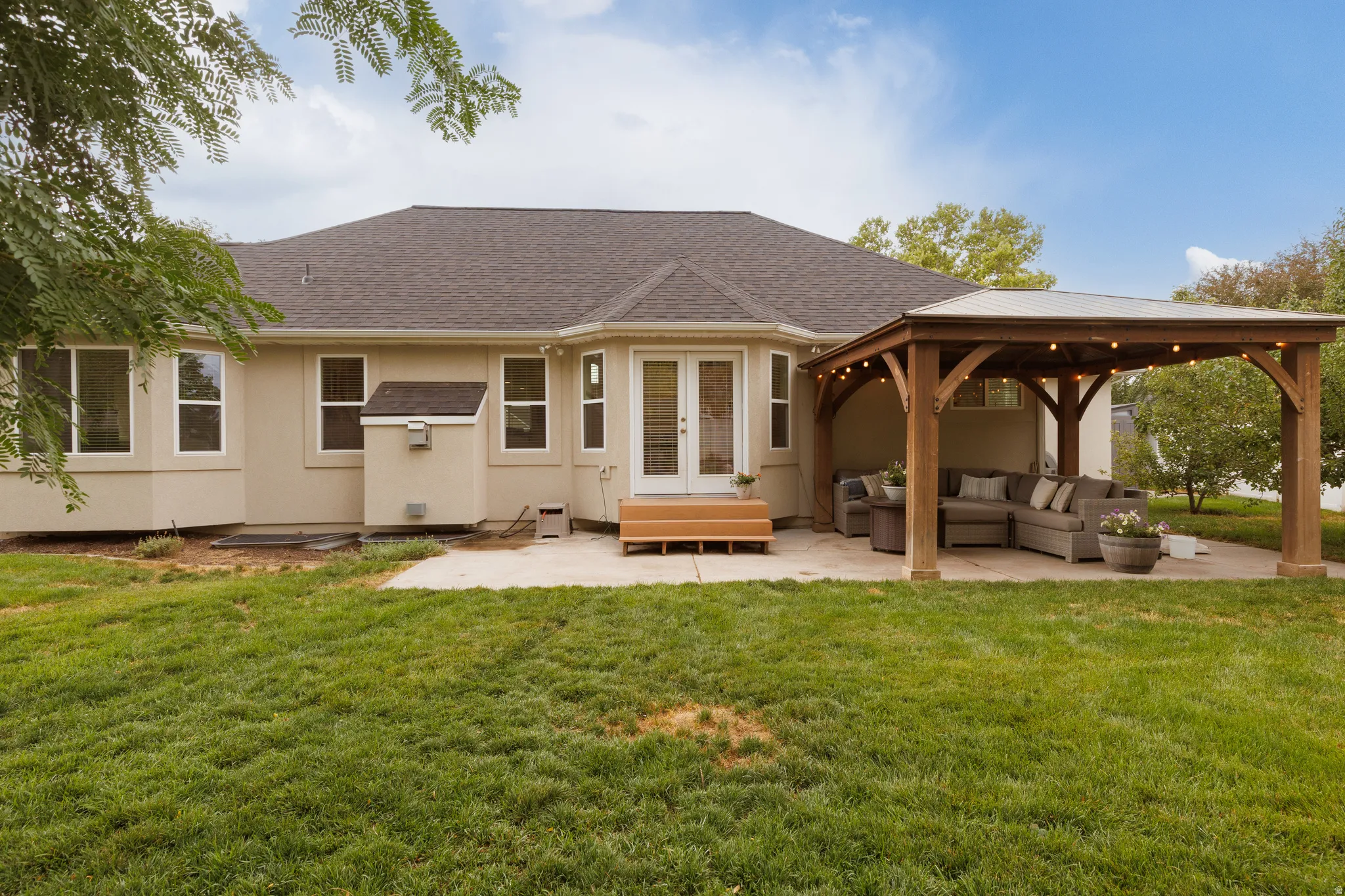 Spacious concrete patio featuring a wood-framed pergola with integrated lighting