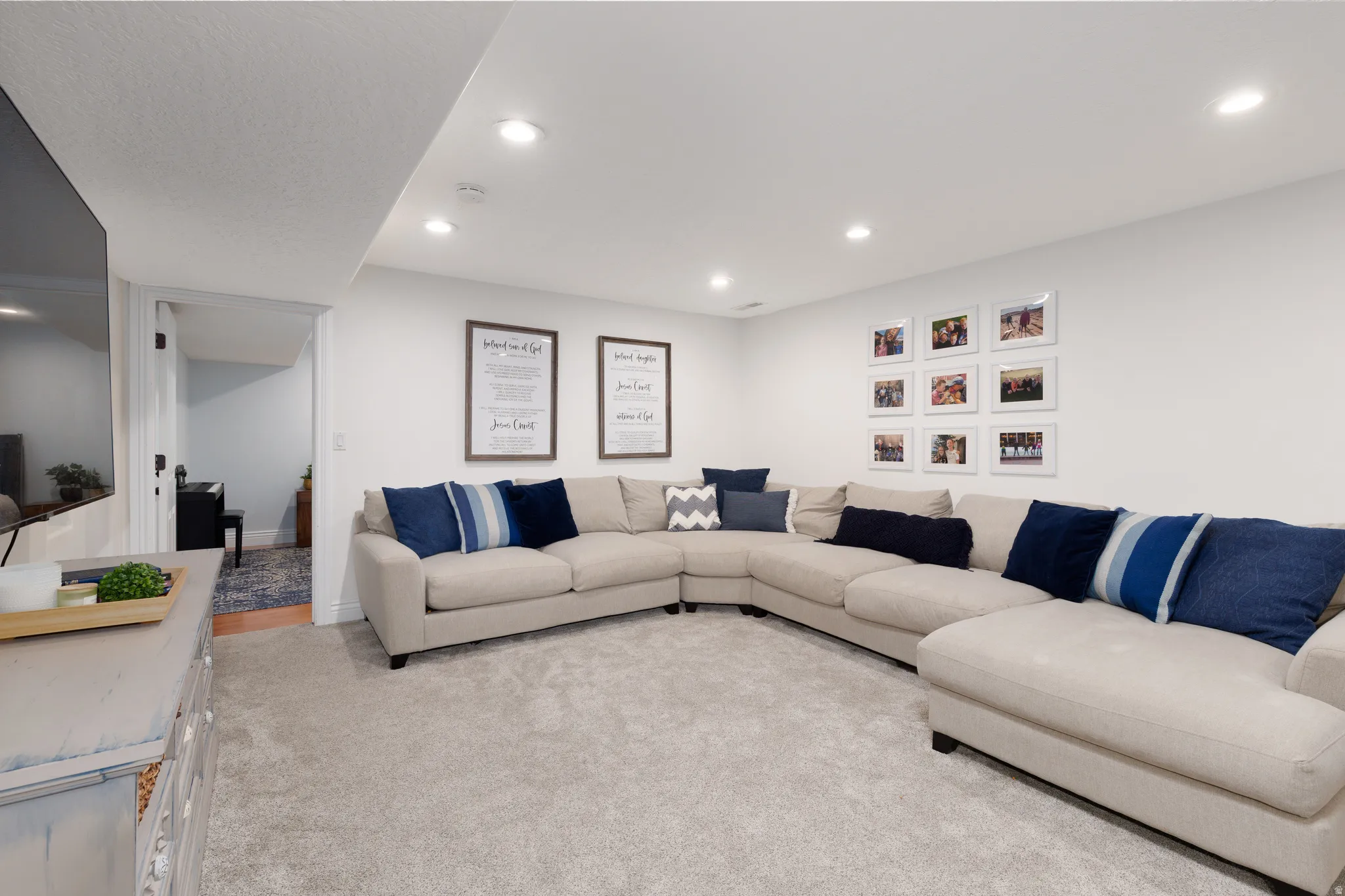 Spacious living area featuring light gray carpeting, recessed ceiling lighting, and white wall finishes