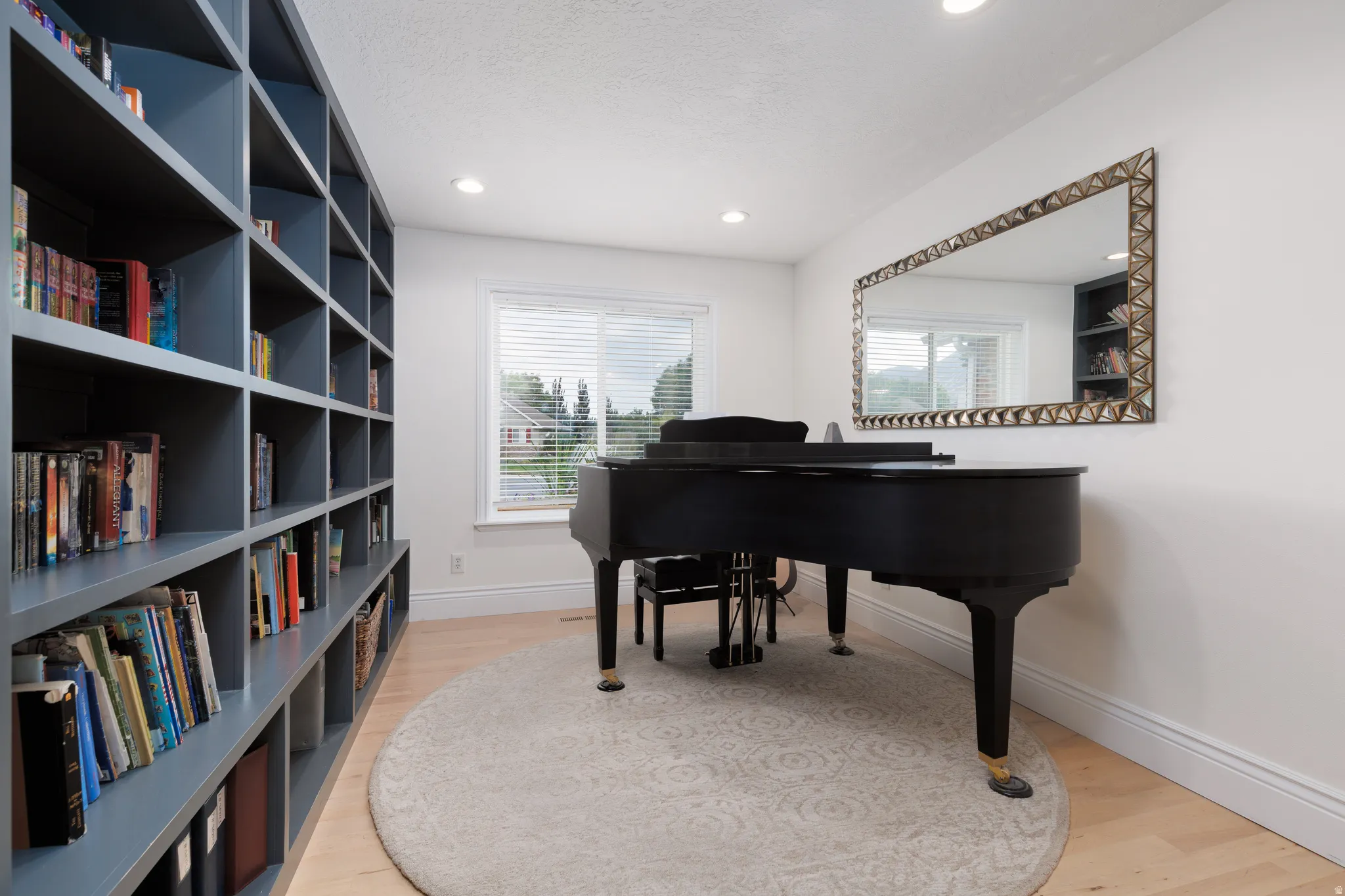 Room featuring an expansive built-in bookcase with a dark finish, wood-finish flooring, and white baseboards